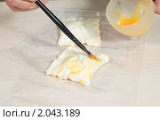 Повар промазывает яичным желтком слойки, готовые к выпечке. Стоковое фото, фотограф Влад Нордвинг / Фотобанк Лори