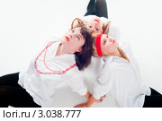 Три девушки сидят на полу, прислонив головы друг к другу на светлом фоне. Стоковое фото, фотограф Сергей Буторин / Фотобанк Лори