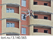 Рабочий-верхолаз заделывает строительные швы на фасаде новостройки (2011 год). Редакционное фото, фотограф Владимир Сергеев / Фотобанк Лори