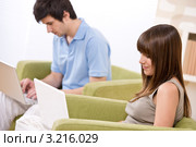 Двое молодых людей работают за лэптопами дома в кресле. Стоковое фото, фотограф CandyBox Images / Фотобанк Лори