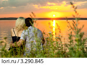 Молодая пара сидит обнвяшись на берегу реки на закате. Стоковое фото, фотограф Алексей Многосмыслов / Фотобанк Лори