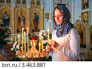 Девушка ставит свечку в православном храме (2012 год). Редакционное фото, фотограф Андрей Ярославцев / Фотобанк Лори