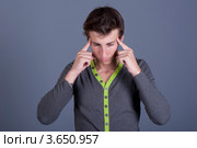 Молодой человек с головной болью держит указательные пальцы у висков. Стоковое фото, фотограф Владимир Белобаба / Фотобанк Лори