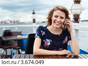 Девушка с телефоном за столиком кафе на набережной. Стоковое фото, фотограф Кекяляйнен Андрей / Фотобанк Лори