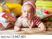Маленькая девочка в чепчике лежит на кровати среди детской одежды. Стоковое фото, фотограф Яков Филимонов / Фотобанк Лори