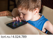Ребенок за столом в кафе играет в игру на телефоне (2012 год). Редакционное фото, фотограф Родион Власов / Фотобанк Лори