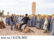 Экскурсовод показывает туристам как правильно садиться на верблюда. Douz, Tunisia (2012 год). Редакционное фото, фотограф Кекяляйнен Андрей / Фотобанк Лори