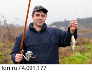 Мужчина с пойманным карасём и удочкой в руках. Стоковое фото, фотограф Игорь Низов / Фотобанк Лори