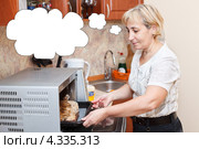 Пожилая домохозяйка достает из микроволновки курицу, запеченную в пакете. Стоковое фото, фотограф Кекяляйнен Андрей / Фотобанк Лори