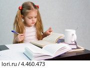 Девочка листает книгу и пишет на листе бумаги конспект сидя за столом. Стоковое фото, фотограф Иванов Алексей / Фотобанк Лори