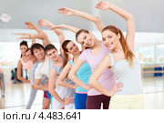 Наклоны в стороны. Молодые люди занимаются фитнесом в зале спортклуба. Стоковое фото, фотограф Raev Denis / Фотобанк Лори