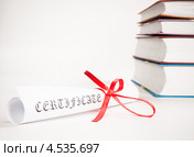 Документ в скрутке перевязанный алой ленточкой на фоне книг. Стоковое фото, фотограф Валерия Лузина / Фотобанк Лори