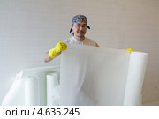 Ремонт квартиры. Строитель держит рулон стелообоев, подготовленный к наклеиванию. Стоковое фото, фотограф Нелли Сабитова / Фотобанк Лори