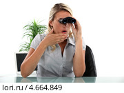 Удивленная девушка смотрит в бинокль, сидя за рабочим столом. Стоковое фото, фотограф Phovoir Images / Фотобанк Лори