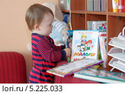 Малыш (1 год 1 месяц) достает с полки детские книги (2013 год). Редакционное фото, фотограф ivolodina / Фотобанк Лори
