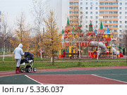 Женщина гуляет вдоль спортивной площадки рядом с детским игровым городком (2013 год). Редакционное фото, фотограф Родион Власов / Фотобанк Лори