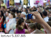 Съёмка смартфоном. Рука со смартфоном на фоне толпы людей. Стоковое фото, фотограф Владимир Заворохин / Фотобанк Лори