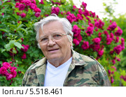 Пожилая женщина-садовод на фоне розового куста. Стоковое фото, фотограф Анна Мартынова / Фотобанк Лори