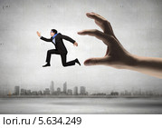 Нечестный бизнес. Мужчина убегает от огромной руки, символизирующей закон. Стоковое фото, фотограф Sergey Nivens / Фотобанк Лори
