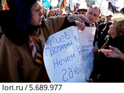 Женщина рвет плакат на митинге в поддержку русских на Украине в Новопушкинском сквере города Москвы 10 марта 2014. Редакционное фото, фотограф Николай Винокуров / Фотобанк Лори