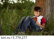 Мальчик с книгой под деревом в летнем парке. Стоковое фото, фотограф Ирина Ращектаева / Фотобанк Лори