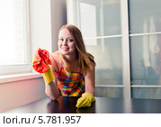 Счастливая евушка полирует стол с помощью полироля для мебели. Стоковое фото, фотограф Валерия Лузина / Фотобанк Лори