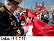 Ветеран Военно морского флота Российской Федерации принимает в пионеры на всероссийской торжественной линейке, посвященной Дню пионерии на Красной площади города Москвы (2014 год). Редакционное фото, фотограф Николай Винокуров / Фотобанк Лори