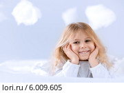 Милая девочка лежит на кровати на фоне облаков и подпирает голову руками. Стоковое фото, фотограф Raev Denis / Фотобанк Лори