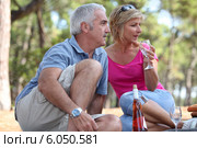 a mid age couple having a picnic in a pine forest. Стоковое фото, фотограф Phovoir Images / Фотобанк Лори