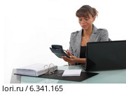 Businesswoman using a calculator at her desk. Стоковое фото, фотограф Phovoir Images / Фотобанк Лори