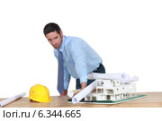 Annoyed architect piling rolled-up drawings on a model. Стоковое фото, фотограф Phovoir Images / Фотобанк Лори