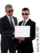 Businessmen wearing sunglasses and looking at a laptop. Стоковое фото, фотограф Phovoir Images / Фотобанк Лори