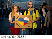 Девушка в одежде цветов российского триколора и мужчина в цветах украинского флага держат табличку "War is over if you want" на "Марше мира" в городе Москве в поддержку украинского народа и против военных действий, 21 сентября 2014. Редакционное фото, фотограф Николай Винокуров / Фотобанк Лори