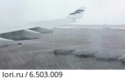 Крыло самолета авиакомпании Finnair стоящего на взлетном поле во время сильного снегопада, вид из иллюминатора (2014 год). Редакционное видео, видеограф Кекяляйнен Андрей / Фотобанк Лори