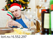 Sick hungover man in Santa hat with glass of water. Стоковое фото, фотограф Яков Филимонов / Фотобанк Лори