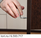 Сборка мебели при помощи г-образного стального шестигранного ключа, который вставлен в мебельный шуруп-стяжку конфирмат. Стоковое фото, фотограф Владимир Григорьев / Фотобанк Лори