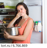 woman holding foul food near refrigerator. Стоковое фото, фотограф Яков Филимонов / Фотобанк Лори