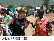Black woman native offers European tourists buy souvenirs production Masai. Пункт контроля на границе Кении и Танзании, город Наманга - местная жительница, женщина племени масаи, предлагает европейской туристке купить  у нее браслеты и другие африканские сувениры. (2008 год). Редакционное фото, фотограф Владимир Григорьев / Фотобанк Лори