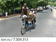 African man rides his  tricycle with body. Двое чернокожих мужчин везут по автомобильной дороге трехколесный велосипед с кузовом, наполненным фруктами, город Дар-эс-Салам, Танзания. (2008 год). Редакционное фото, фотограф Владимир Григорьев / Фотобанк Лори