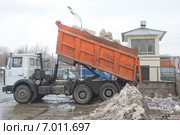 Разгрузка грязного снега из кузова оранжевого автомобиля в снегодробилку на снегоплавильном пункте, Москва (2015 год). Редакционное фото, фотограф Малышев Андрей / Фотобанк Лори