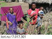 Women and children in the village of Maasai near huts. Масаи за защитным ограждением из колючих кустов, семья из двух чернокожих женщин и двух маленьких детей, Аруша, Танзания. (2008 год). Редакционное фото, фотограф Владимир Григорьев / Фотобанк Лори