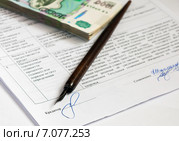 Покупка недвижимости с помощью ипотеки. Пачка тысячных купюр и ручка лежат на кредитном договоре. Фокус на подписи (2015 год). Редакционное фото, фотограф Игорь Низов / Фотобанк Лори