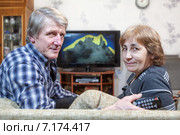 Пожилая пара сидит на диване перед телевизором и смотрит, обернувшись назад. Стоковое фото, фотограф Кекяляйнен Андрей / Фотобанк Лори