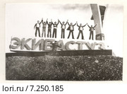 Восемь молодых людей стоят подняв руки на каменных буквах при въезде в город  Экибастуз 1970год (2015 год). Редакционное фото, фотограф Emelinna / Фотобанк Лори
