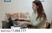 Молодая женщина работает на ноутбуке в помещении за столом. Стоковое видео, видеограф Кекяляйнен Андрей / Фотобанк Лори