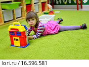Маленькая девочка играет в детском саду, лежа на полу. Стоковое фото, фотограф Ирина Борсученко / Фотобанк Лори