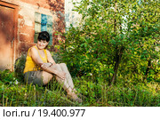 Весёлая женщина среднего возраста сидит возле кирпичного сарая (2015 год). Редакционное фото, фотограф Игорь Низов / Фотобанк Лори