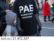 Женщина с ребенком идет на шествии в черной футболке с надписью "Раб валютной ипотеки" в центре города Москвы, Россия (2015 год). Редакционное фото, фотограф Николай Винокуров / Фотобанк Лори