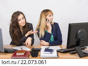 Ситуация в офисе - одна сотрудница разговаривает по телефону, другая просит у ней телефон. Стоковое фото, фотограф Иванов Алексей / Фотобанк Лори