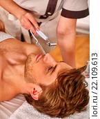 Young man enjoying electric facial massage. Стоковое фото, фотограф Gennadiy Poznyakov / Фотобанк Лори